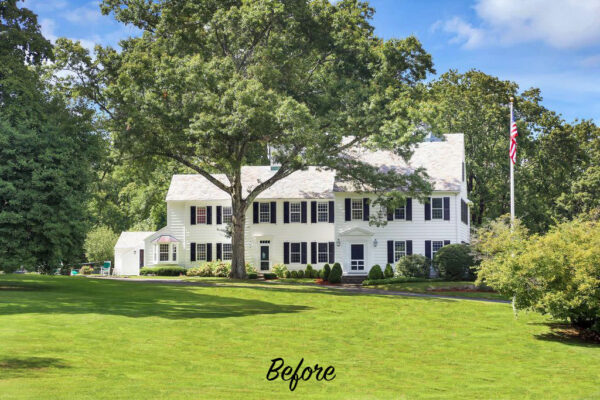 A large, white colonial-style house with black shutters and a gray roof is surrounded by lush greenery and trees under a clear blue sky. An American flag is on a pole to the right, and the word Before is written at the bottom center of the image.